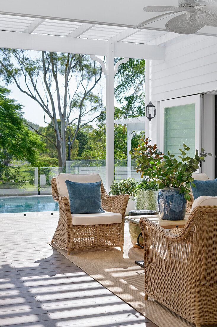 Covered terrace with rattan furniture and pool view