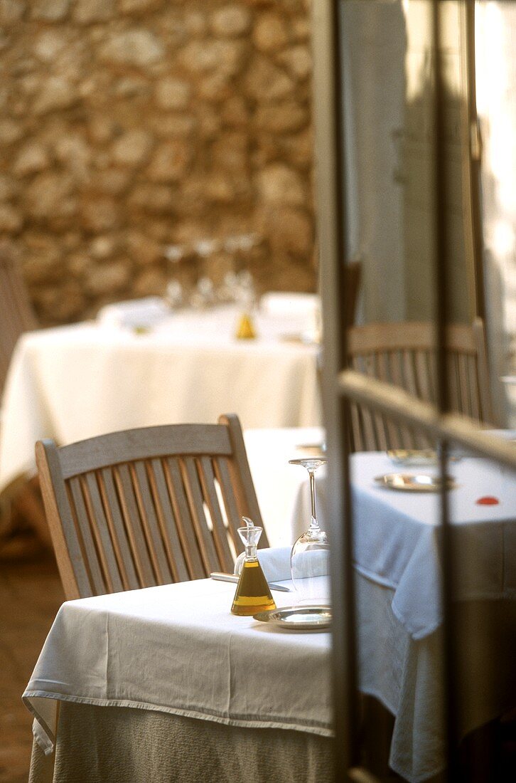 In Erwartung von Gästen gedeckte Tische auf der Terrasse eines Lokals im französisch mediterranen Stil
