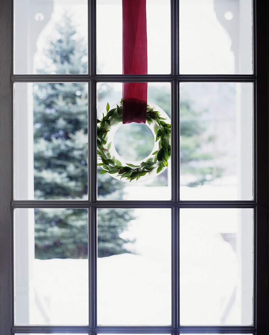 Weihnachtskranz aus Eis und Zweigen an einer Glastür