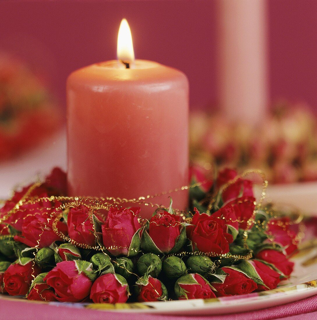 Rosa Kerze mit Kranz aus Rosenblüten als Tischdeko