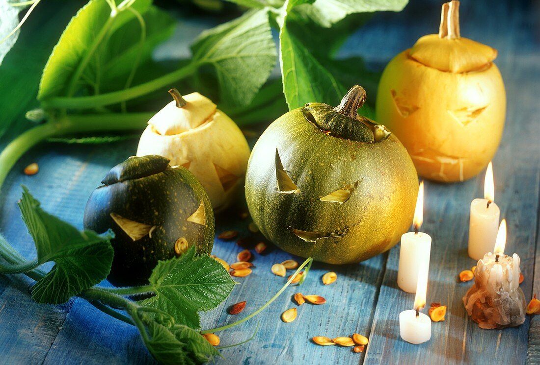 Halloween pumpkins on blue wooden table, candles nearby