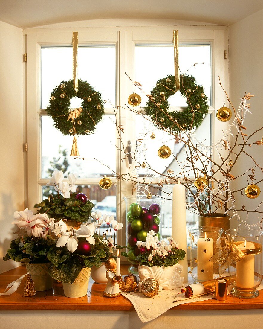 weiße Weihnachtsfensterdeko mit Kerzen, Pflanzen etc.