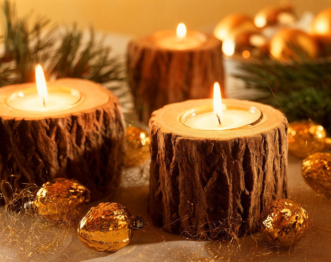 Brennende Teelichter in Baumstümpfen als Weihnachtsdeko
