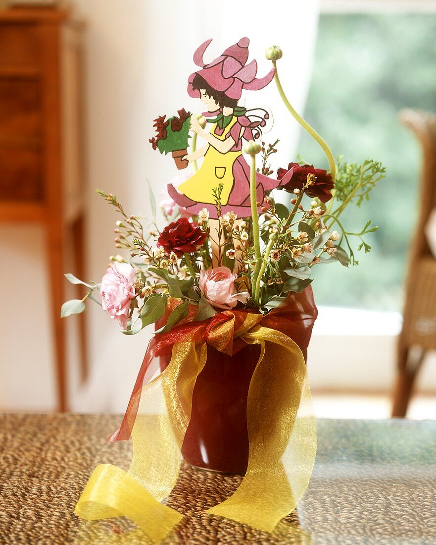Flower arrangement in shades of red with wooden figure
