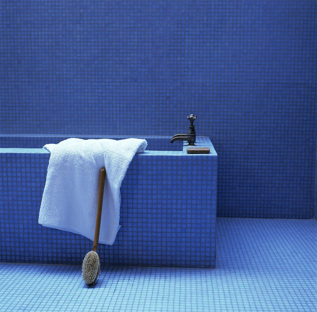 Gemauerte Wanne mit Armatur im Antikstil in blauem Badezimmer mit Mosaikfliesen