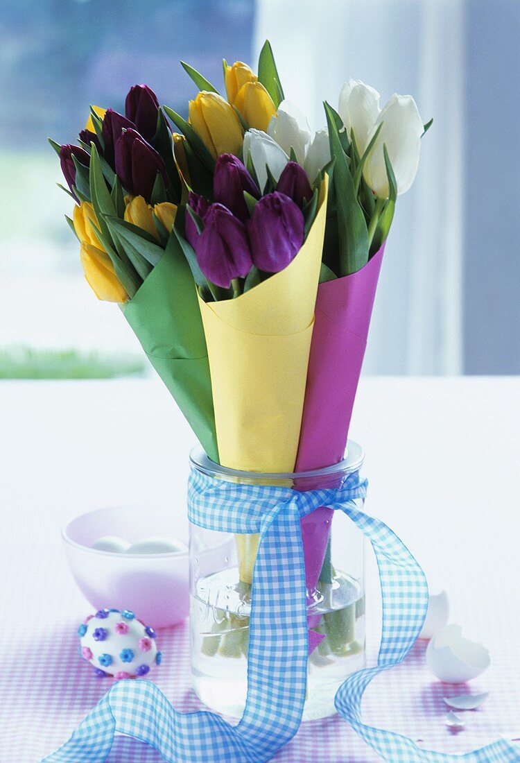 Tulips in glass with blue bow, Easter eggs beside it