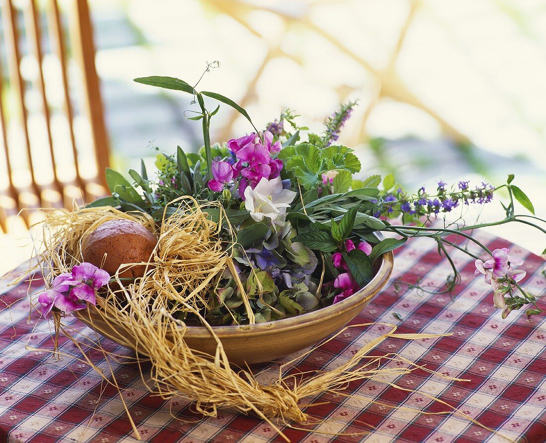 Terracotta bowl of summer flowers decorated with raffia
