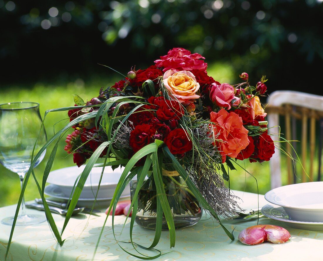 Bäuerlicher Rosenstrauss mit Gräsern auf gedecktem Tisch