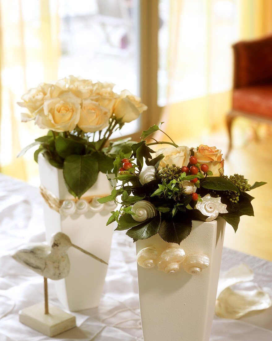 Champagne-coloured roses in decorated vases