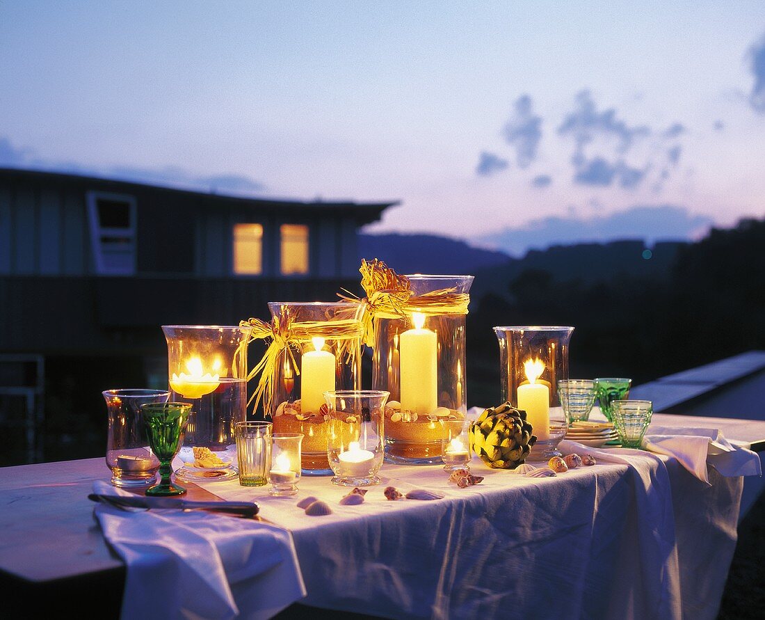Tisch mit leuchtenden Windlichtern in der Dämmerung