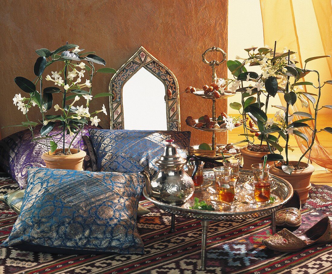 Tray of Middle Eastern tea glasses, cushions & Stephanotis
