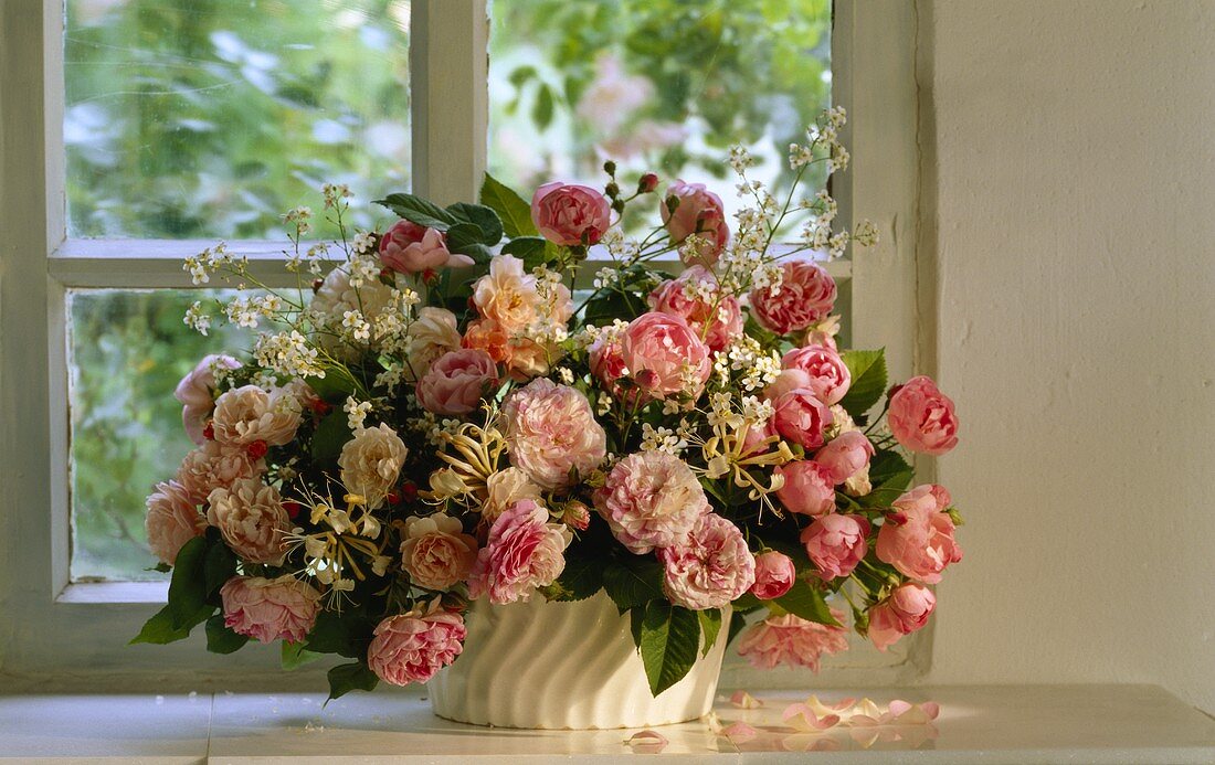 Blumenstrauss mit rosa Rosen vor dem Fenster