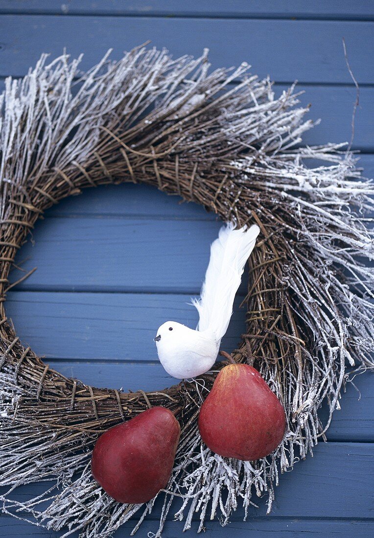Wreath with pears & an artificial bird on blue wooden wall