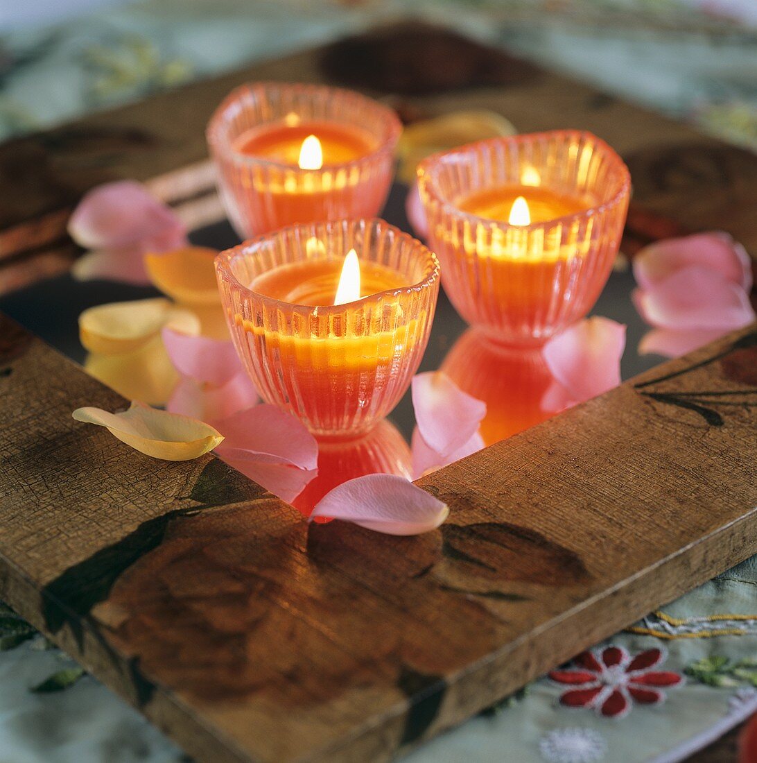 Three candles and rose petals on a table