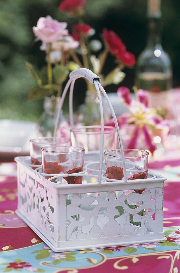 Glasses painted with roses standing in a glass carrier