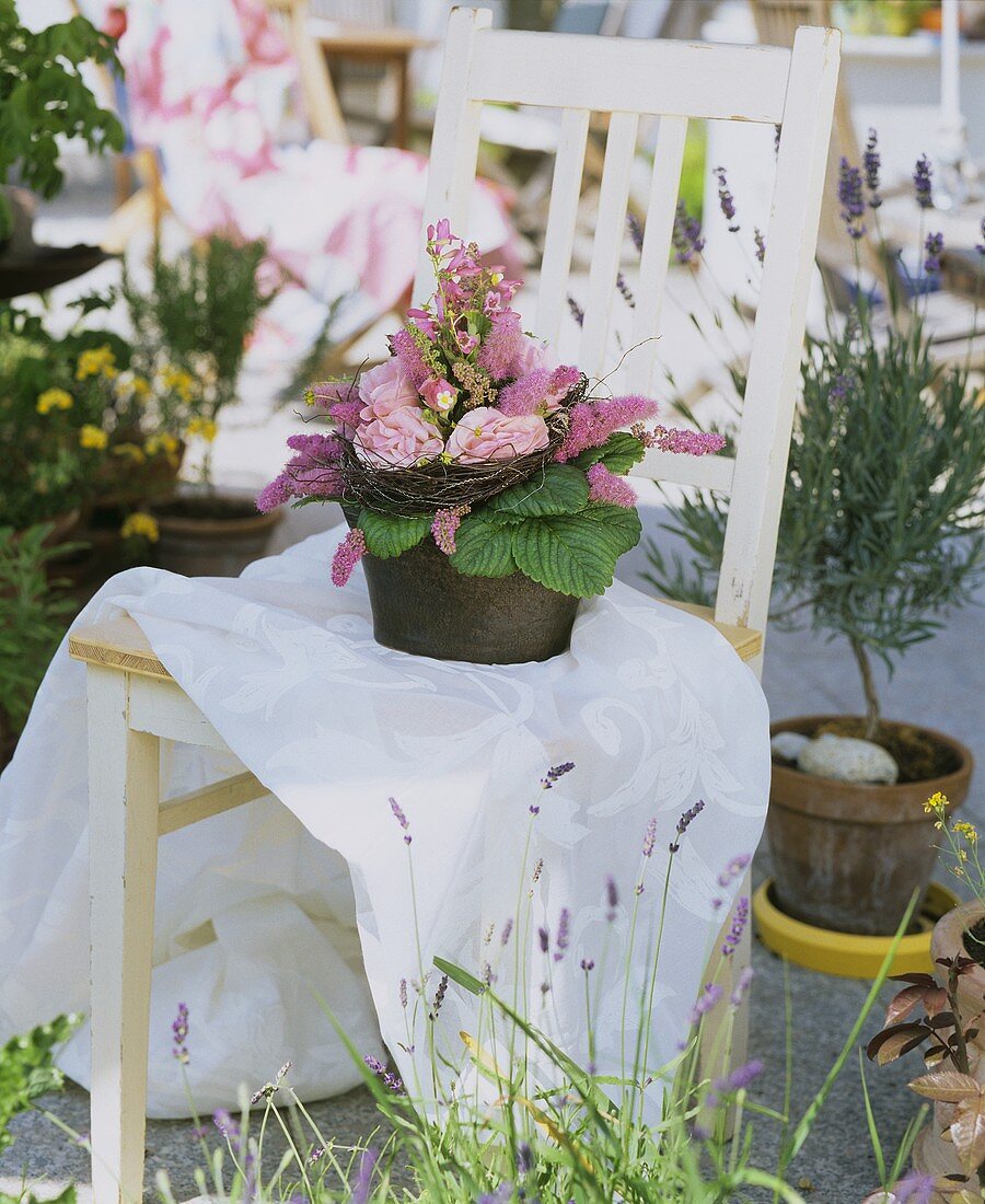 Blumengesteck auf einem Stuhl im Freien