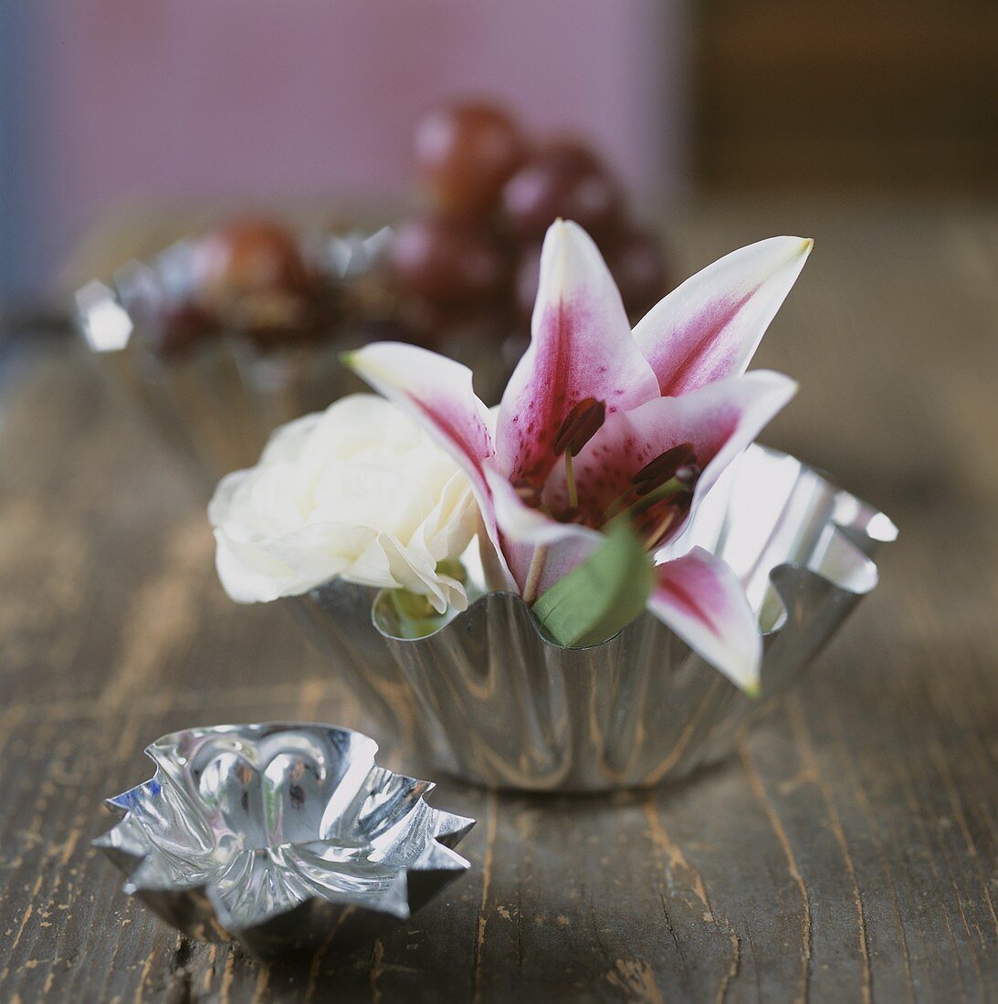 A lily and a white rose in a small silver bowl