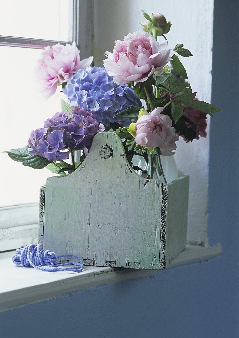 Purple hydrangeas and pink peonies on windowsill