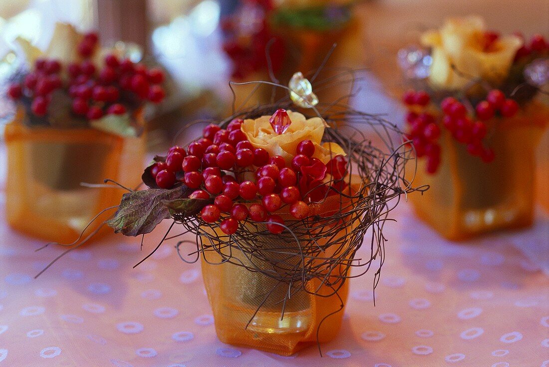 Table arrangements of berries & roses in tulle-covered glasses