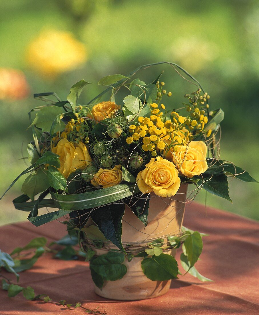 Arrangement: yellow roses, vine tendrils, small chrysanthemums