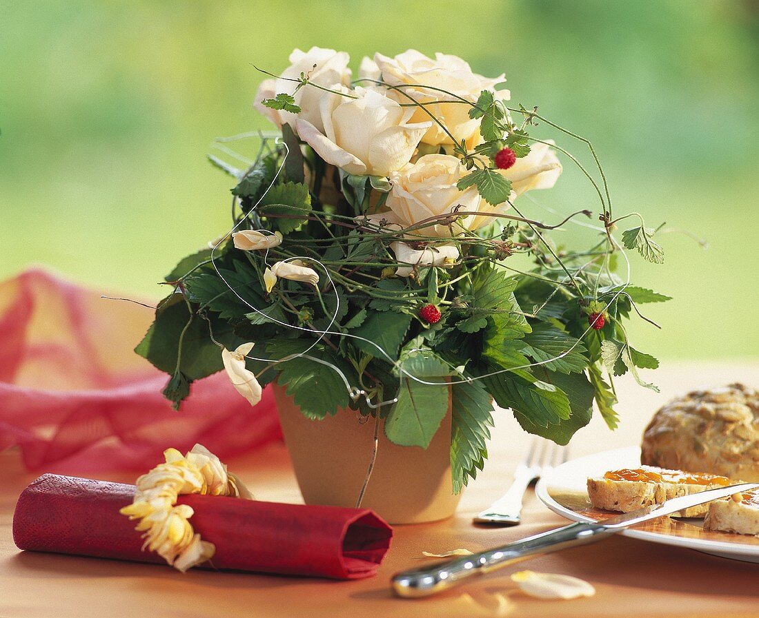 Tischgesteck mit weissen Rosen und Walderdbeerranken