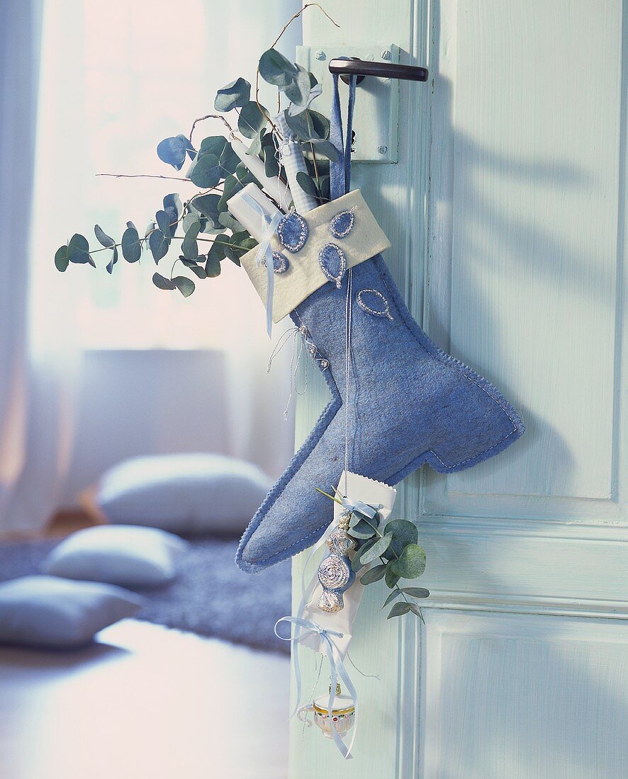 Felt boot on the door with presents & eucalyptus branches