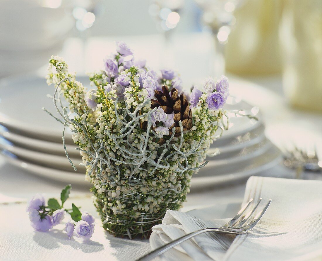 Winter arrangement of white heather, fir cones & bluebells