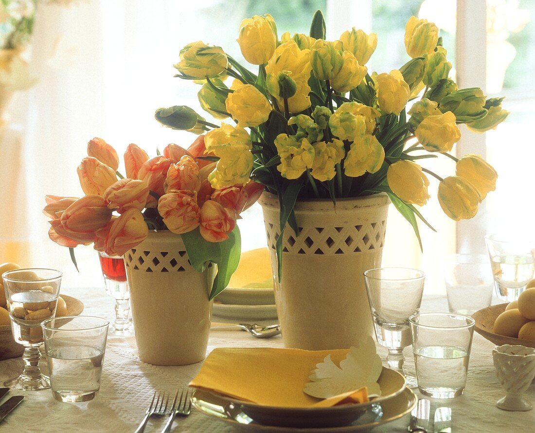 Gelbe & gelbrote Tulpen in gelben Blumenvasen am Ostertisch