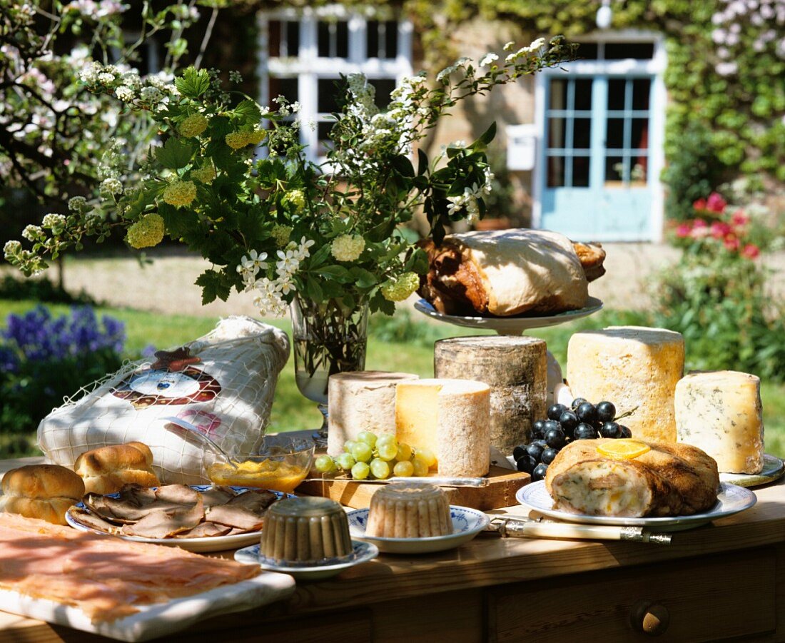 Buffet mit alten französischen Käsen und Schinken im sommerlichen Garten