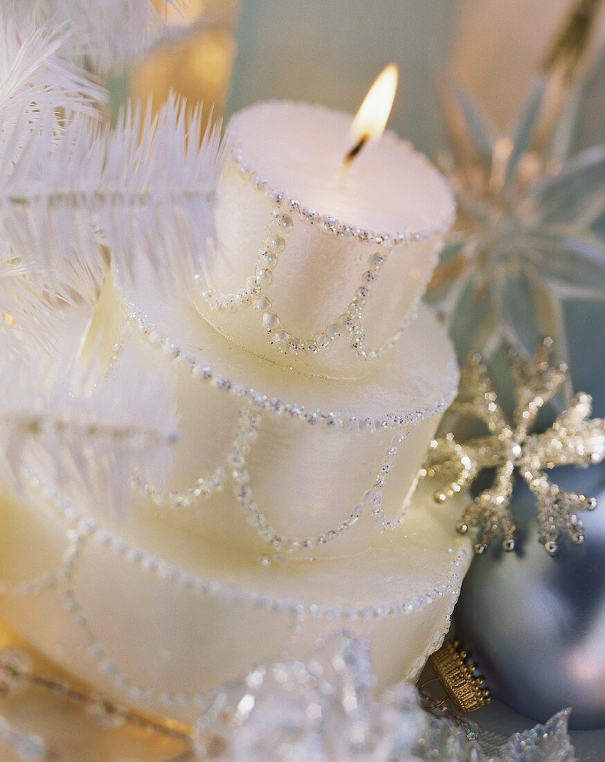 White candle in shape of three-tiered Christmas cake
