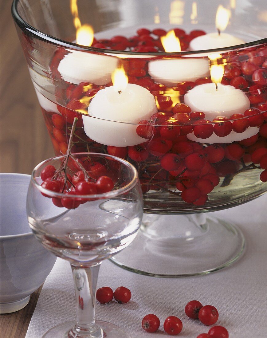 Table decoration: bowl of white floating candles and rose hips
