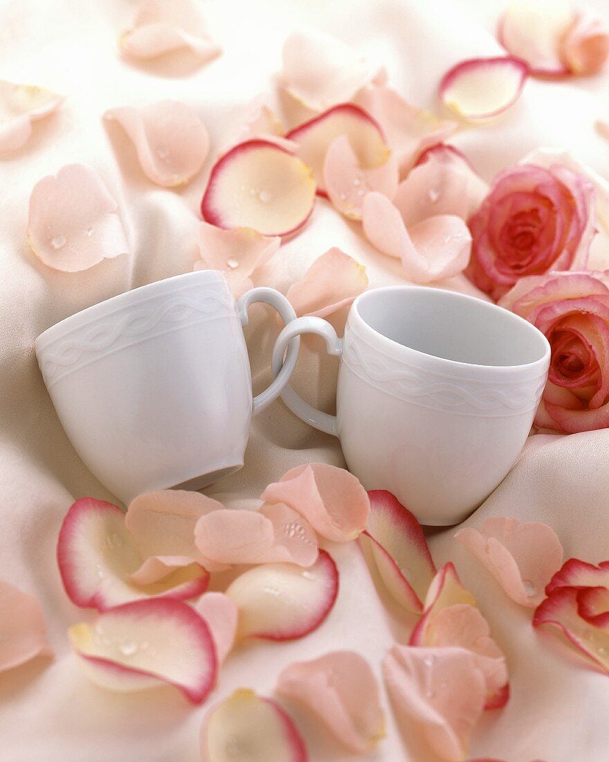 Verschlungene Tassen mit Rosenblättern