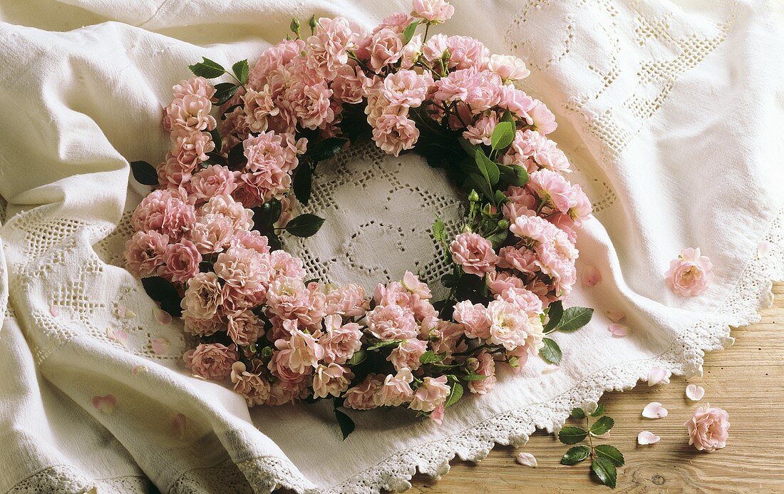 Kranz aus rosa Rosen auf Spitzendecke