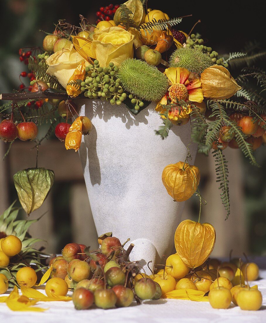 Herbstliches Blumenarrangement mit Früchten in Steinvase
