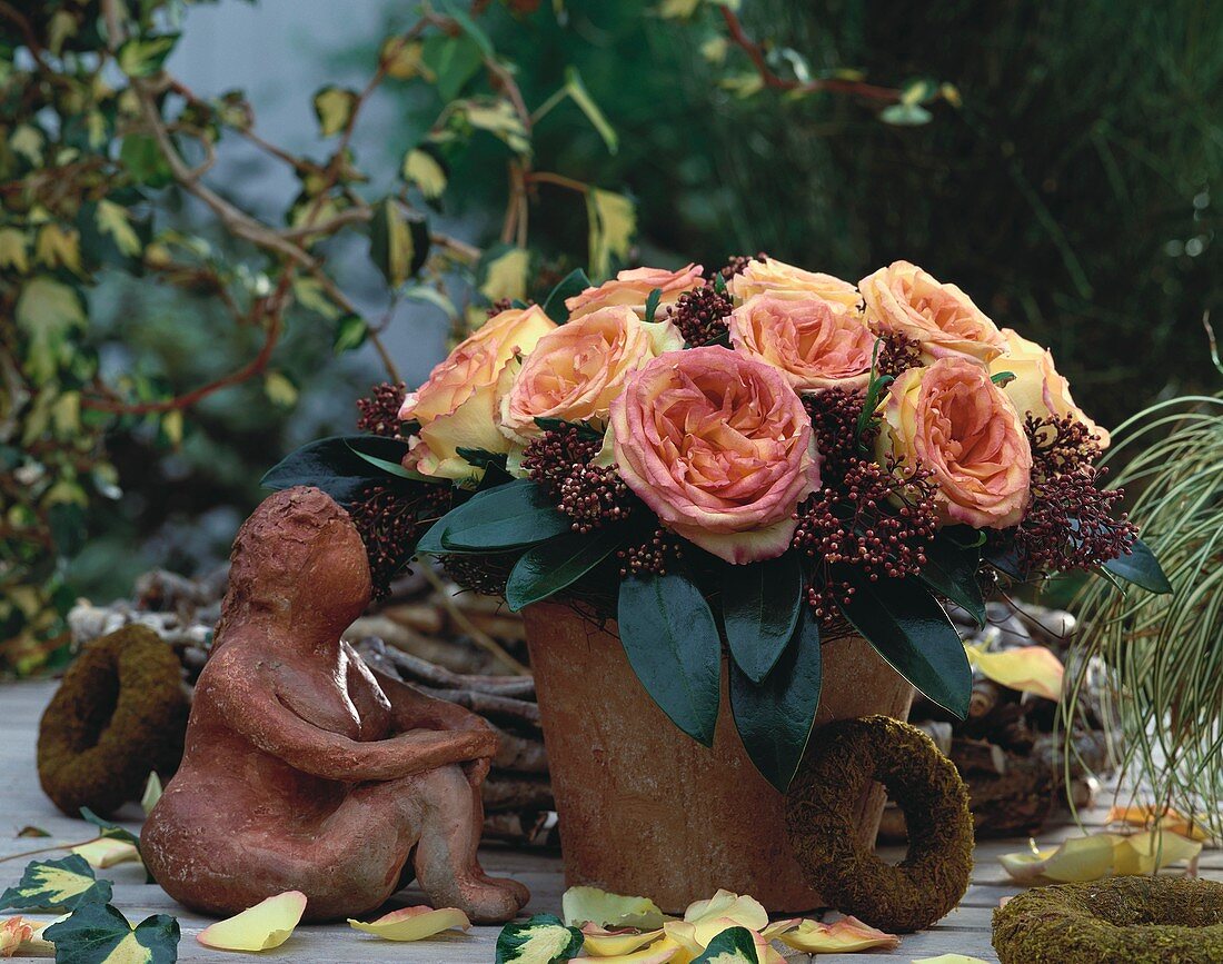 Herbstlicher Rosenstrauss im Tontopf, daneben Tonfigur