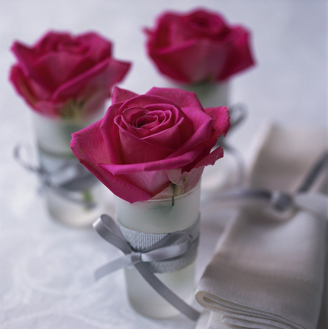 Tischdeko mit roten Rosen in Gläsern