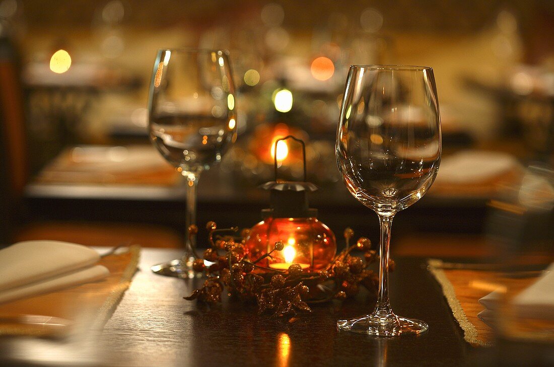 Weingläser und Windlicht auf gedecktem Tisch im Restaurant