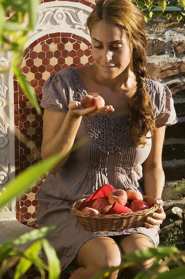 Frau mit Pfirsichen auf Gartenstuhl