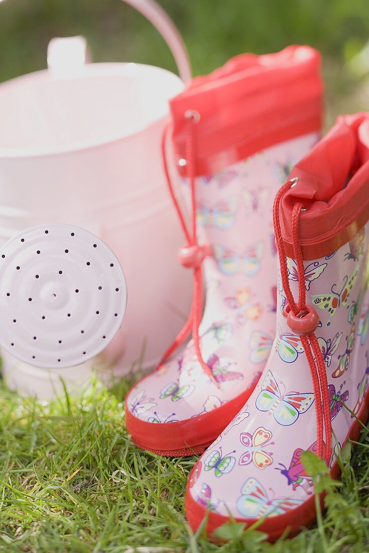 Child's rubber boots and watering can on grass