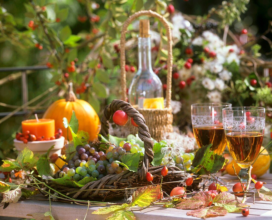 Herbstlicher Tisch mit Weintraben, Blättern, Kerzen und Wein