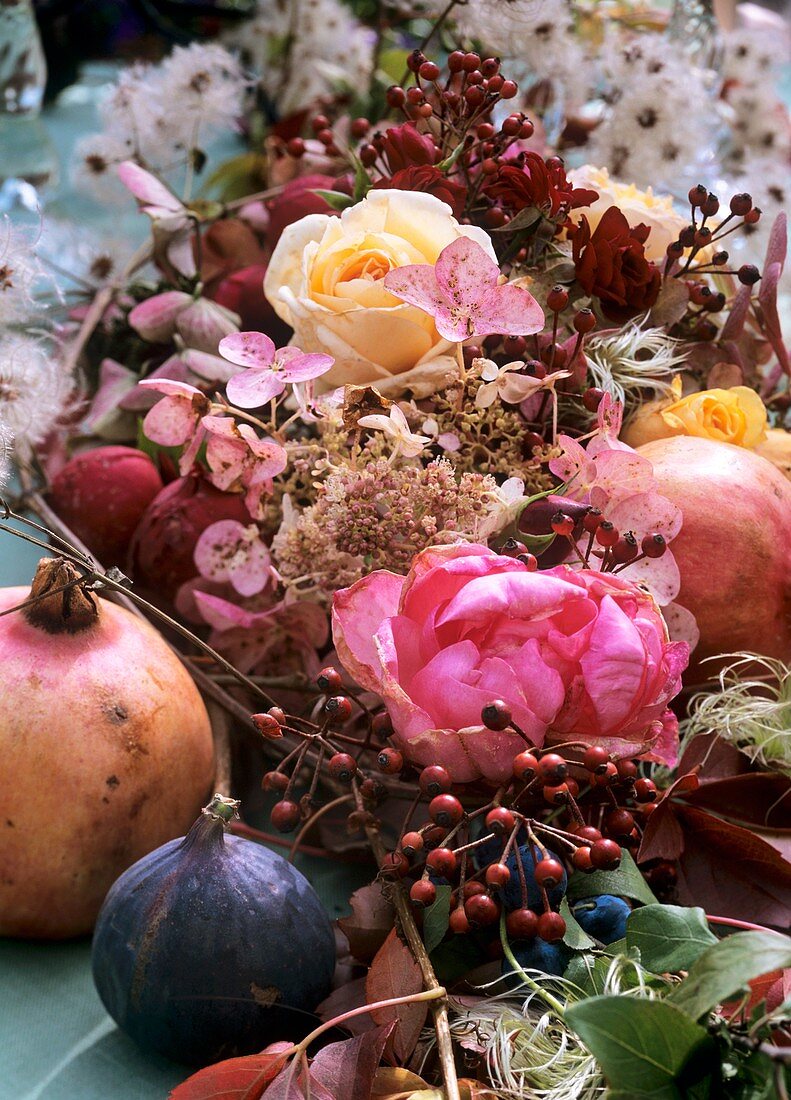 Festliche Tischdeko mit Rosen, Hagebutten und Granatäpfeln