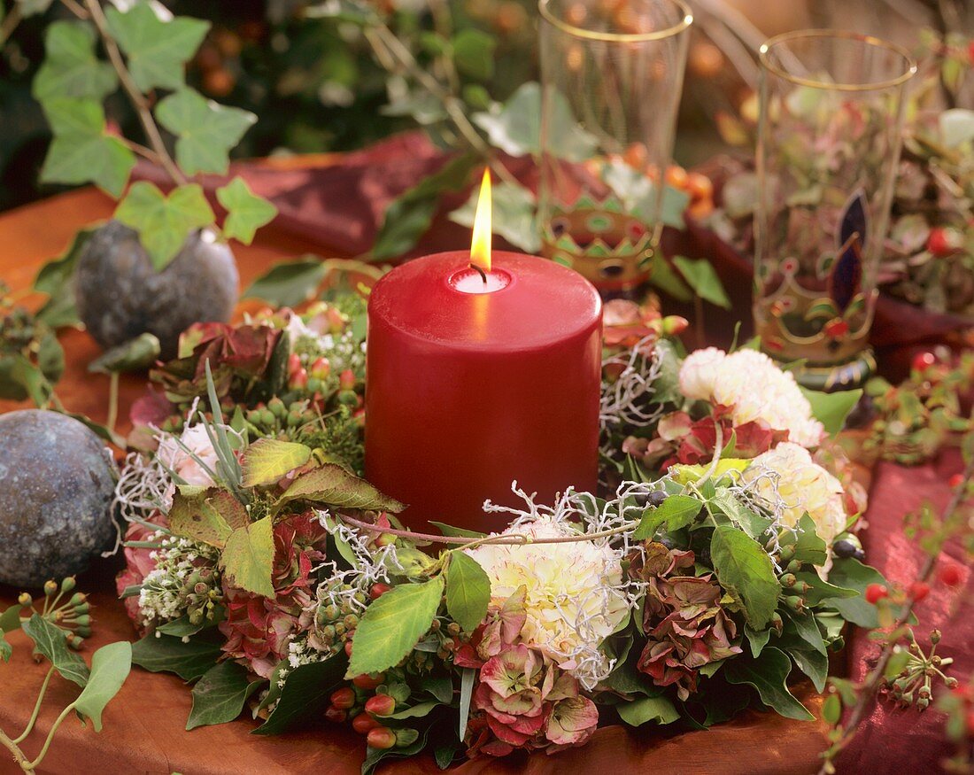 Tischkranz aus Nelken, Hortensien, Efeu, Stacheldraht, Johanniskrautfrüchte und Kerze