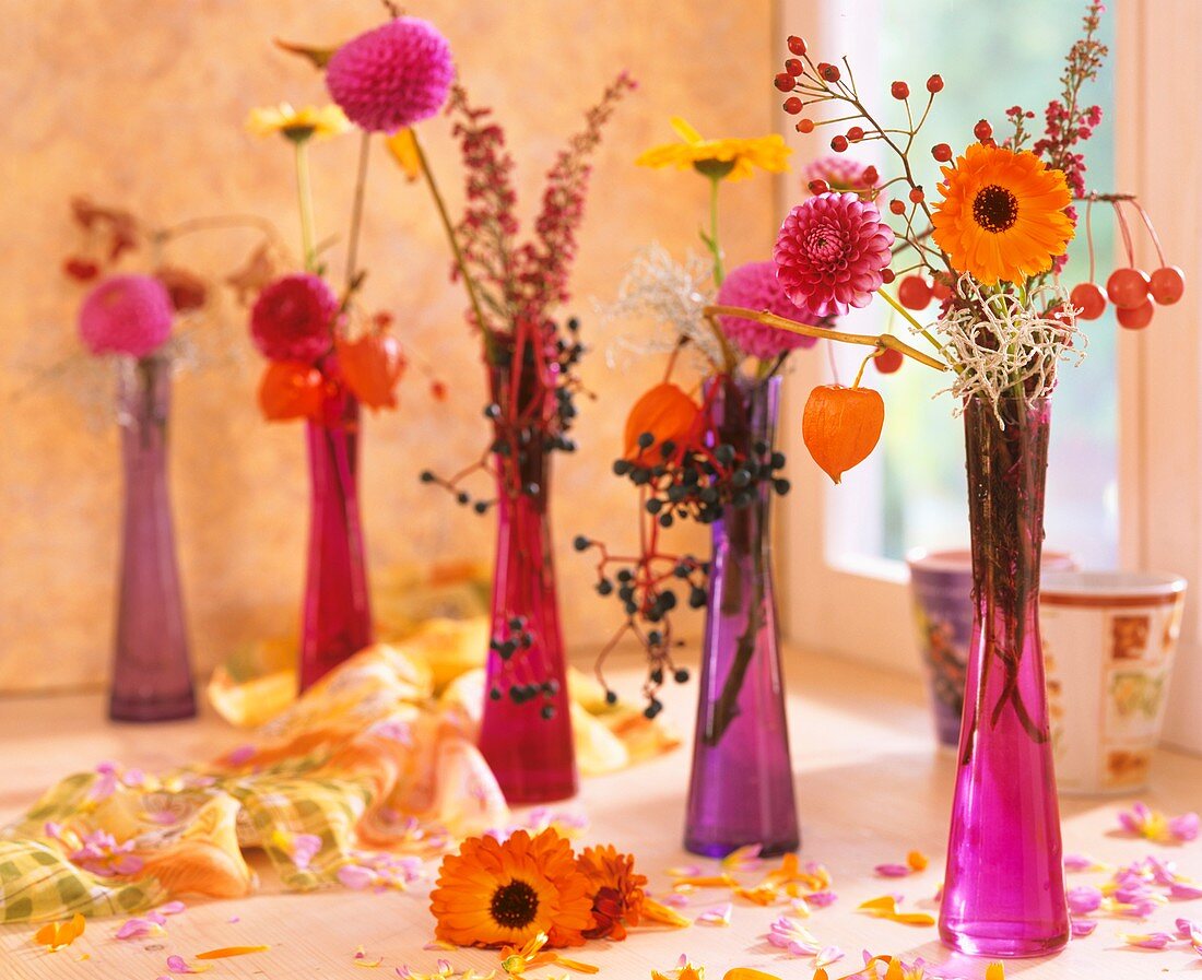 Glass vases of dahlias, marigolds, rose hips, heather