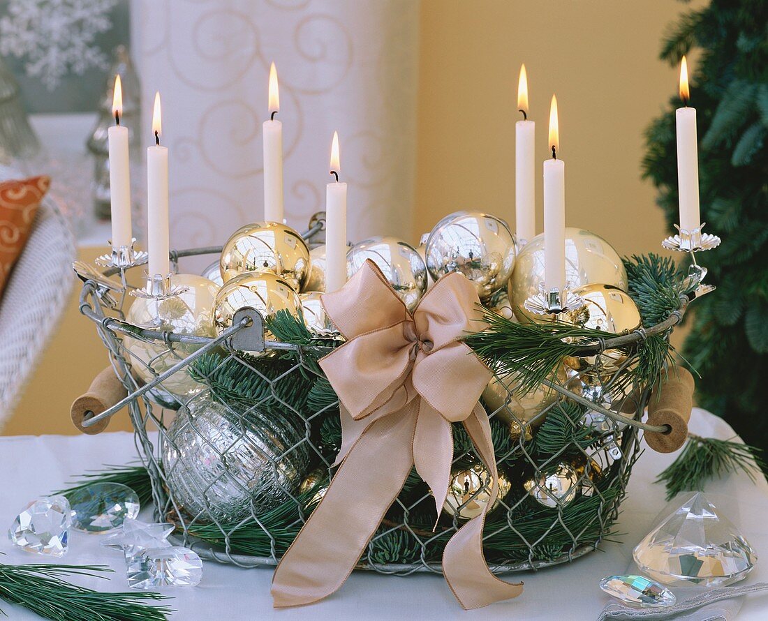 Christmas baubles, candles and greenery in wire basket