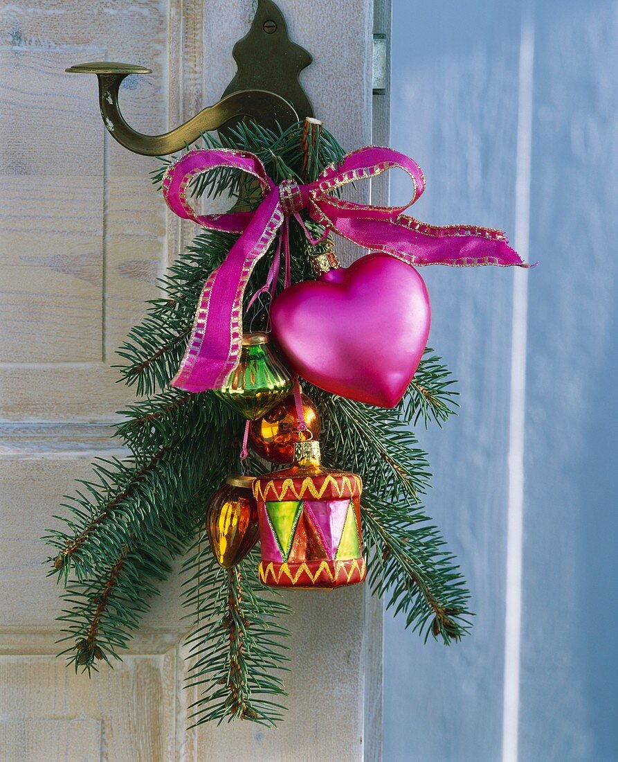 Spruce branch with tree ornaments on a door handle