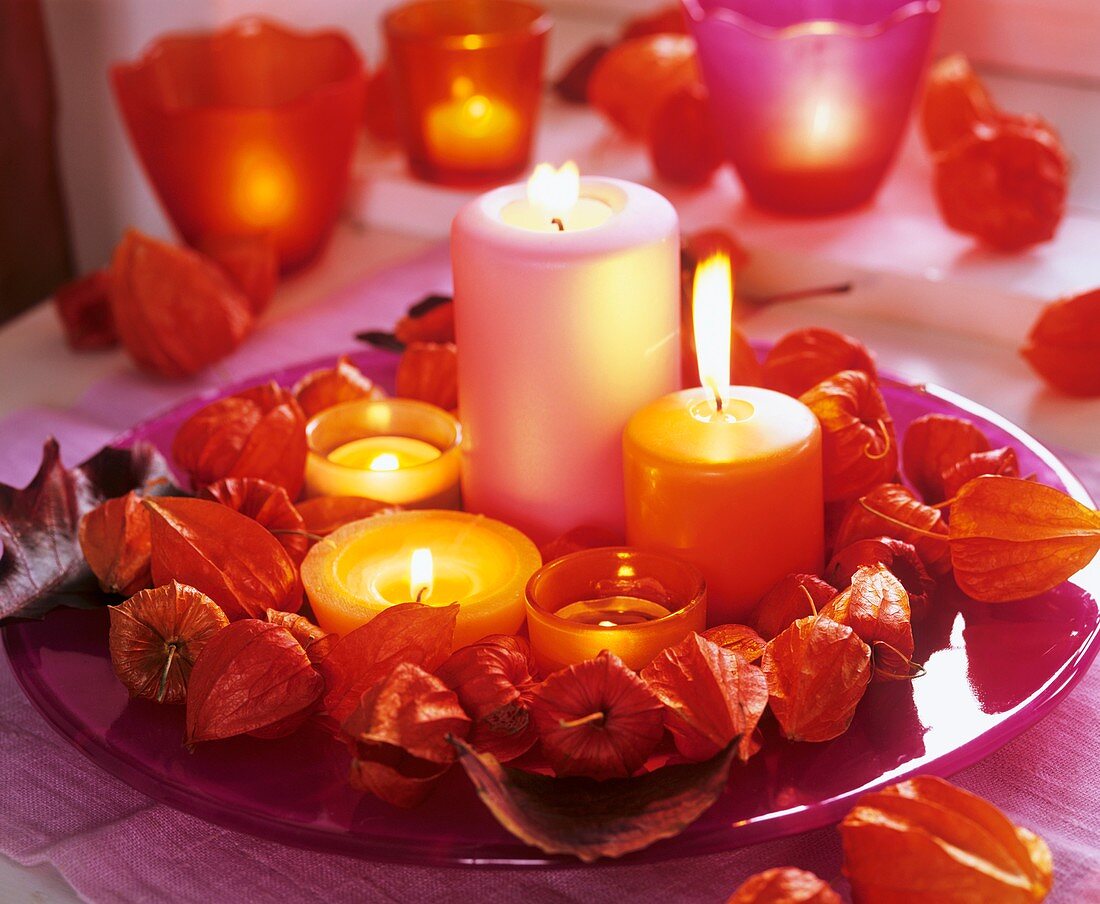 Pinker Glasteller mit Kerzen mit Kranz aus Lampionblume