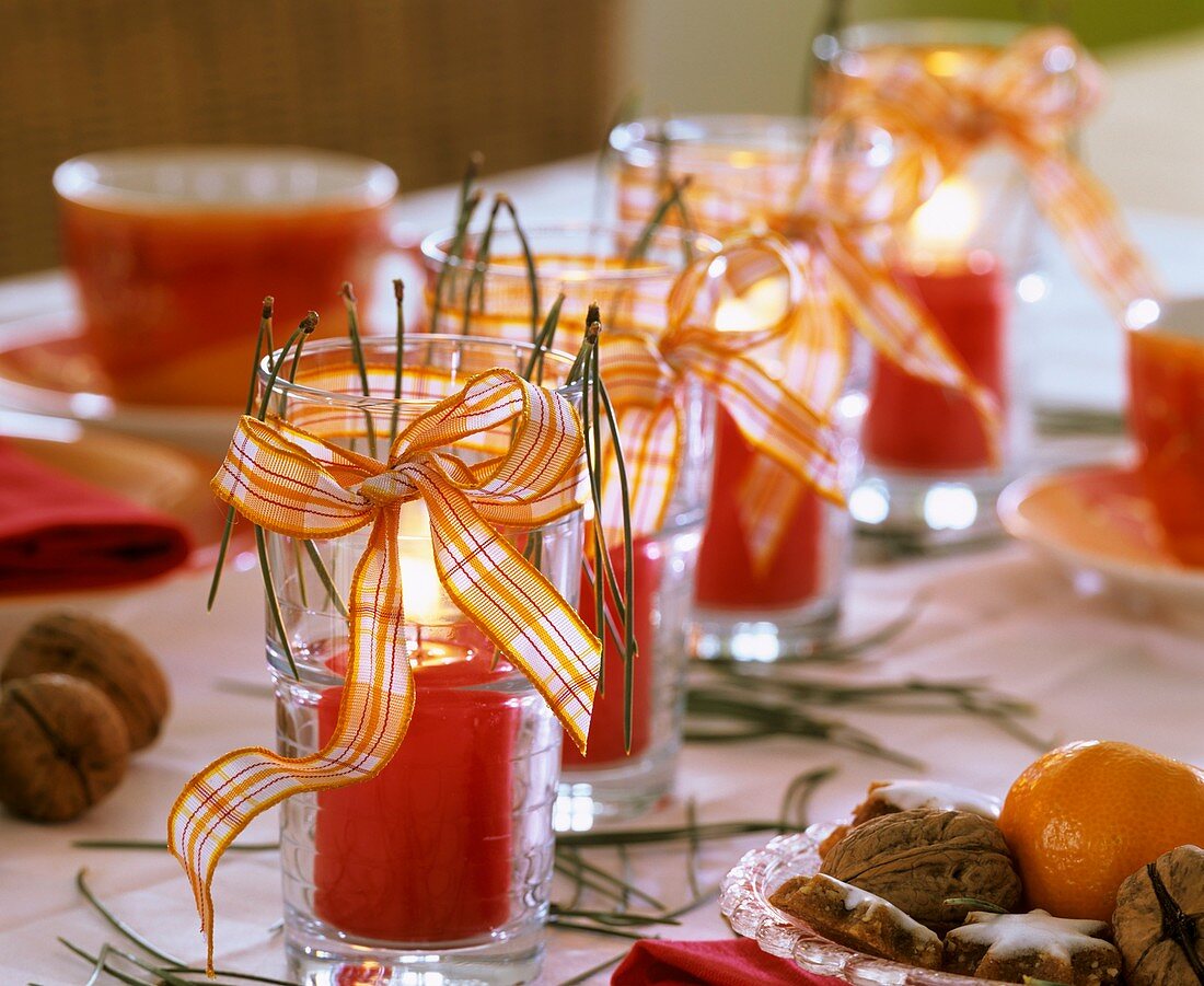 Red candles in drinking glasses with checked ribbons