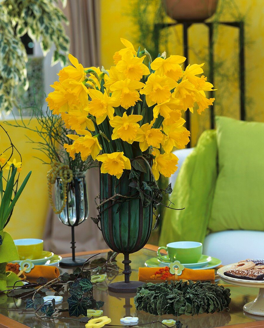 Table with daffodils, coffee cups and small cakes