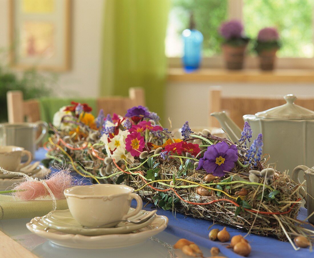 Tisch mit Blumengirlande, Tassen und Kanne