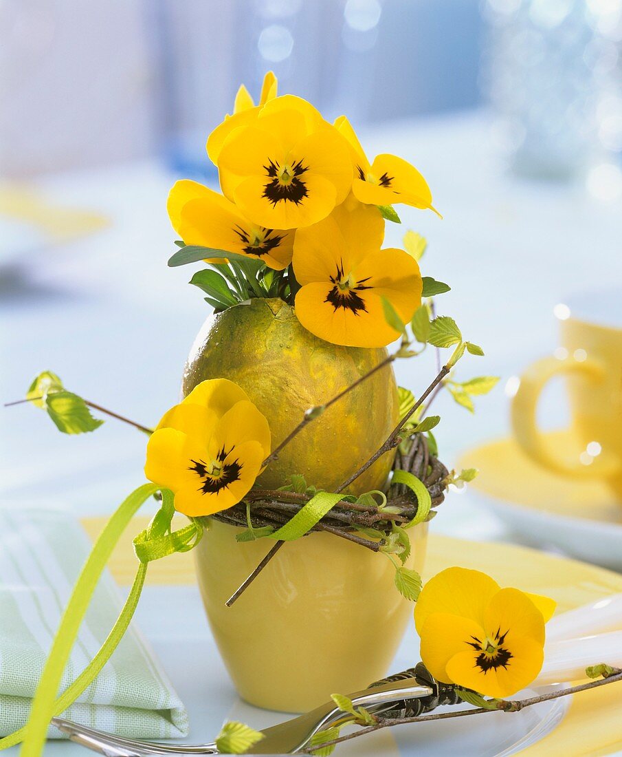 Yellow horned violets in golden egg vase with eggcup 